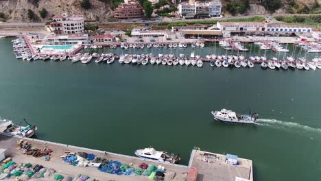 Vista-Aérea-De-Un-Barco-Entrando-En-El-Tranquilo-Puerto-De-Arenys-De-Mar-Cerca-De-Barcelona,-España