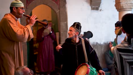 Side-shot-of-man-playing-a-rhaita-or-mizmar-as-men-play-large-tamborine-or-def-and-other-drums-with-hands-and-sticks