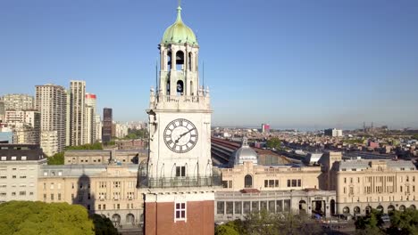 Toma-Orbital-De-La-Torre-Monumental-Del-Reloj-Con-La-Estación-De-Tren-Retiro-Al-Fondo,-Buenos-Aires