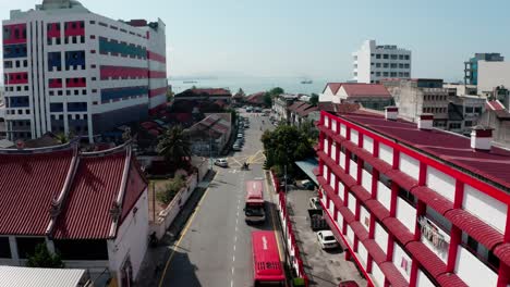 Aerial-view-of-Chulia-Street-with-Pantai-Fire-and-Rescue-Station-the-right-and-ocean-in-the-distance,-Drone-dolly-flyover-reveal-shot