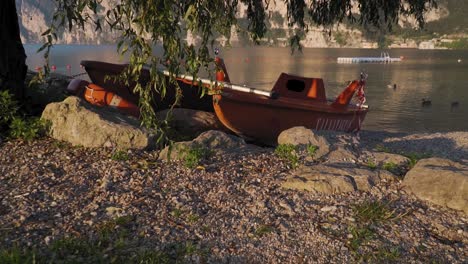 Altes-Boot-Am-Seeufer-Verlassen,-Morgendliche-Seelandschaft,-Goldenes-Sonnenlicht