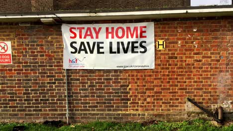 ‘Stay-Home--Save-Lives’-virus-warning-sign-in-housing-estate,-Fulham,-London,-UK