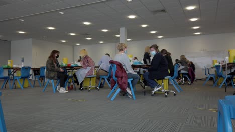 People-waiting-preparing-to-take-covid-AstraZeneca-vaccine-jab-in-UK-centre