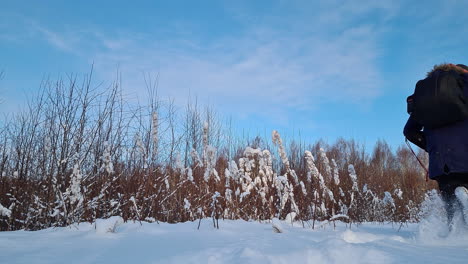 Person-walking-through-deep-snow-with-winter-equipment,-close-up-low-angle-view