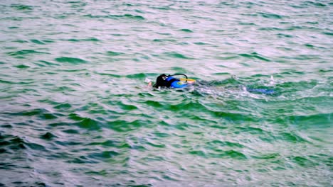 A-man-teaching-another-how-to-dive-in-the-sea-near-the-surface-in-Bombas-and-Bombinhas-beaches,-Brazil