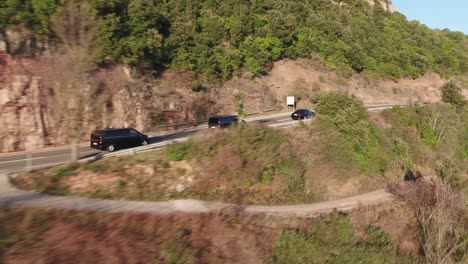 Vehicles-Traveling-On-Cliffside-Pavement-Road-During-Summer-In-Montserrat,-Spain