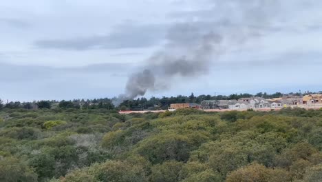 Humo-Oscuro-Que-Sale-De-Un-Viejo-Edificio-De-Fort-Ord-Abandonado-Cerca-De-Casas-Recién-Construidas-En-Marina,-California