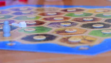 Strategy-board-game-Catan,-being-played-by-a-few-players-and-settlements-and-roads-being-placed-on-the-board