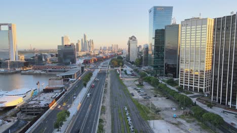 Carretilla-Aérea-En-La-Autopista-Paseo-Del-Bajo-Entre-Los-Muelles-De-Puerto-Madero-Y-Los-Rascacielos-Al-Atardecer,-Buenos-Aires