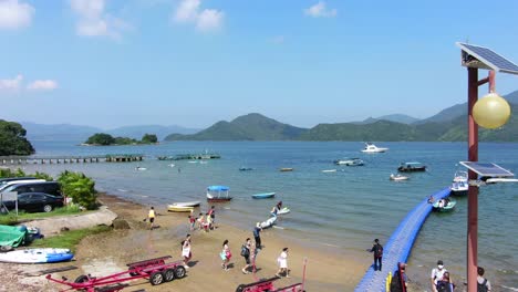 Einheimische-Gehen-An-Einem-Sommertag-Auf-Einem-Kleinen-Pier-In-Hongkong-Mit-Kleinen-Booten-Im-Wasser