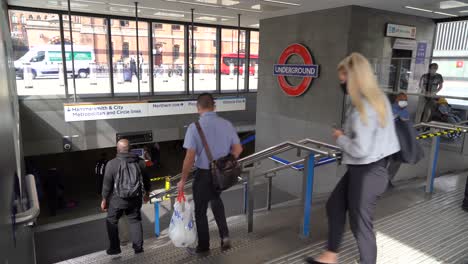 Personas-Con-Máscaras-Faciales-Mientras-Bajan-Las-Escaleras-Y-Entran-En-La-Estación-Kings-Cross-St-Pancras-Station,-Londres,-Reino-Unido