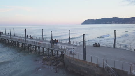 Gente-En-El-Muelle-De-Alassio-Junto-Al-Mar-En-Liguria,-Norte-De-Italia