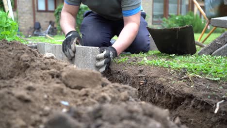 Jardinero-Tocando-El-Nivel-De-Losa-De-Piedra-Con-Ladrillo,-Tiro-De-ángulo-Bajo