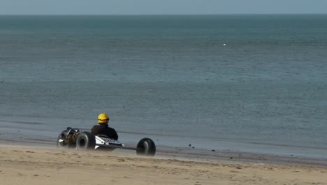 Kitebuggy-drives-along-the-sea-on-the-beach-of-Brouwersdam,-slow-motion,-The-Netherlands