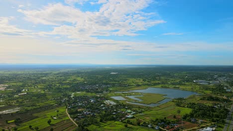 Por-Encima-De-La-Vista-Aérea-Moviéndose-Y-Viendo-El-Campo-Pantanoso-Con-La-Carretera-Un-Día-Soleado-En-Khonkaen,-Tailandia