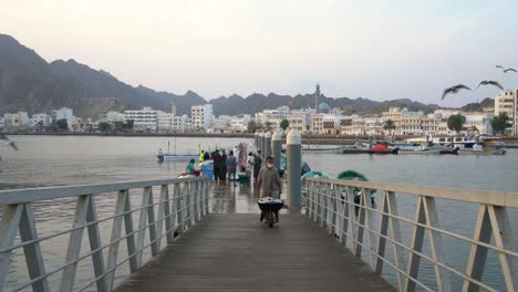 Pescadores-En-Un-Muelle-Descargando-Su-Captura-Diaria-Con-Una-Persona-Que-Lleva-Pescado-En-Una-Carretilla-En-Mutrah