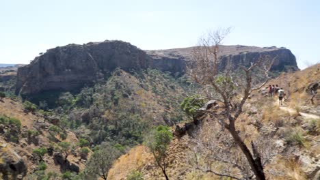 Hikers-walk-along-mountain-trail-in-Isalo-National-Park,-Madagascar