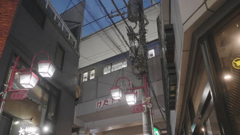 Tren-De-Transporte-Público-Que-Viaja-Por-La-Ciudad-Pasando-Por-Un-Rascacielos-Durante-La-Noche-En-Tokio,-Japón