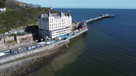 Aerial-view-of-The-Grand-hotel-landmark-Llandudno-seafront-seaside-Victorian-promenade-tourism-building-slow-left-orbit