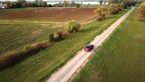 Vista-Aérea-De-Un-Coche-Opel-Grandland-Negro-Y-Rojo-Acelerando-En-Una-Carretera-De-Campo