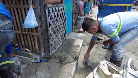 Foremen-wearing-safety-reflective-vests-used-their-shovel,-mixed-cement,-and-demolition-hammer-to-perform-excavation-beside-the-road-gutter-to-install-new-water-piping-from-the-main-water-line