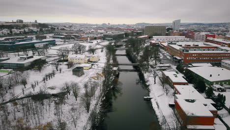 Luftaufnahme-Eines-Industriegebiets,-Das-Nach-Dem-Ersten-Schneefall-Vom-Fluss-Durchquert-Wird,-Schweden