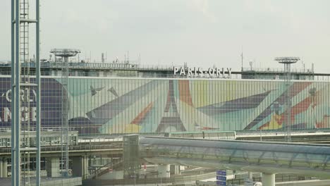 Establecimiento-De-Una-Vista-Alta-Del-Edificio-Del-Aeropuerto-De-París-Orly-Con-Tráfico-Y-Metro