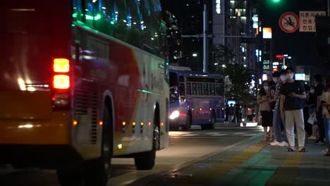 Nighttime-view-of-the-Gangnam-bus-stop-station-in-downtown-Seoul-with-people-lined-up-to-ride-wearing-face-masks-to-protect-against-COVID-infection