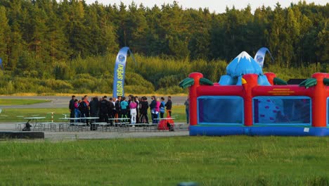 Group-of-professional-skydivers-in-jumpsuits-discussing-after-a-successful-high-altitude-parachute-jump,-sunny-summer-evening,-golden-hour,-medium-distant-shot