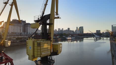 Construction-cranes-and-buildings-by-river-in-Buenos-Aires,-aerial