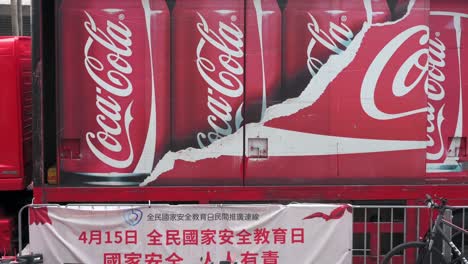 Los-Peatones-Pasan-Junto-Al-Logotipo-De-La-Marca-Estadounidense-De-Refrescos-Coca-Cola-Que-Se-Muestra-En-Su-Camión-De-Reparto-De-La-Marca-En-Hong-Kong.