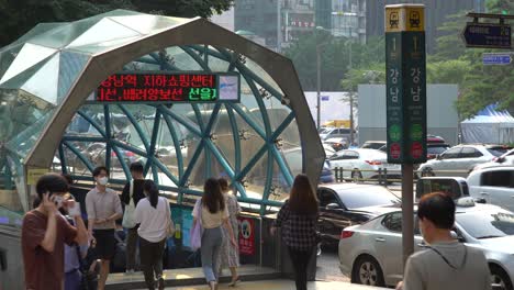 Gangnam-Station-Exit-1,-People-Walking-At-The-entrance-to-Gangnam-Station-During-Rush-Hour-In-Seoul-on-Sunset,-South-Korea-With-City-Traffic-In-Background