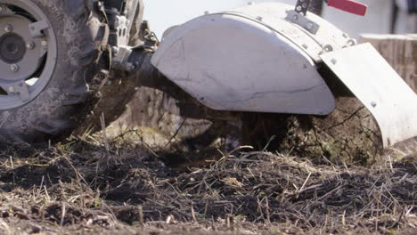 A-rototiller-moves-topsoil-around,-agriculture-in-Sweden,-slow-motion-close-up