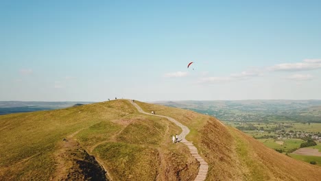 Luftdrohnenaufnahme-Von-Menschen-Auf-Dem-Gipfel-Des-Mam-Tor,-Castleton,-Peak-District-Und-Einem-Gleitschirmflieger-Folgend