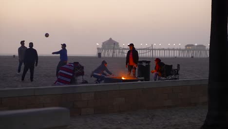 Amigos-Disfrutando-De-La-Noche-Alrededor-De-Una-Fogata-En-Huntington-Beach,-California