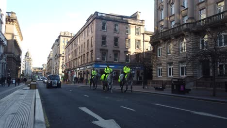 Una-Toma-Amplia-De-Un-Grupo-De-Policías-Y-Sus-Caballos-Bajando-Por-Una-Carretera-De-La-Ciudad