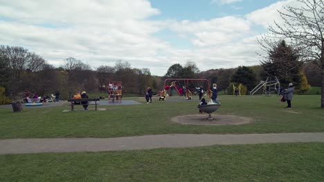 Children-and-kids-playing-on-swings-and-slides-and-having-fun-in-an-outdoor-public-park-during-the-day,-springtime