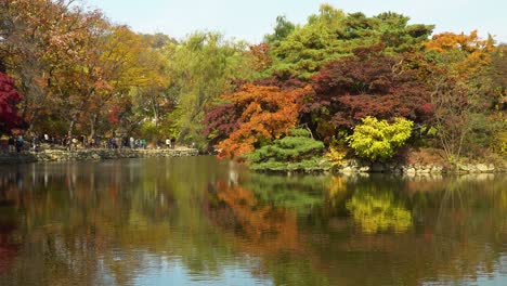 Chundangji-pond-skyline-with-Korean-people-walking-by-the-stone-pagoda,-Changgyeonggung-Palace,-Seoul-South-Korea