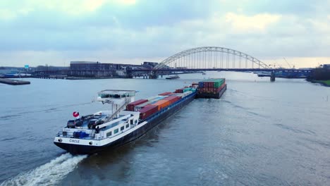 Luftaufnahme-Des-Hecks-Eines-Kreisförmigen-Binnencontainerschiffs,-Das-Sich-Brug-über-De-Noord-Nähert