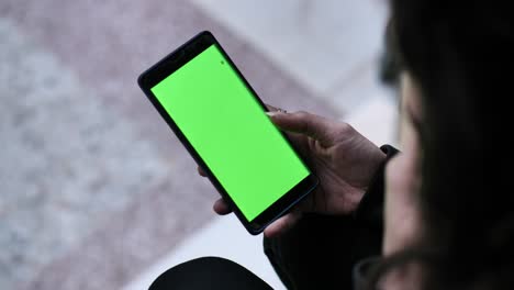 Over-Left-Shoulder-Shot-Of-Hipster-Pakistani-Woman-Holding-A-Green-Screen-Mobile