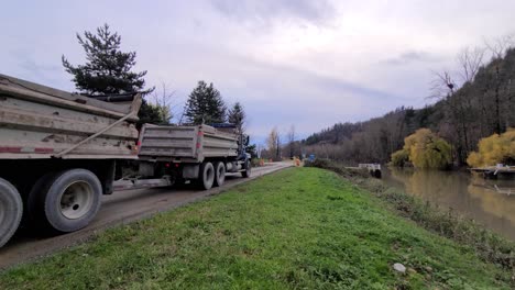 A-blue-truck-with-containers-driving-along-the-river-then-took-a-turn-at-the-end