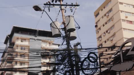 Primer-Plano-Inclinado-Que-Revela-Un-Desorden-De-Cableado-En-Un-Poste-Urbano,-Múltiples-Cables-Y-Conexiones-Proporcionan-Energía-Y-Comunicación-A-Los-Residentes-Y-Negocios-Locales,-Ciudad-De-Panamá