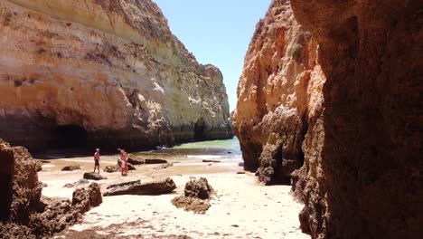 Praia-dos-Tres-Irmaos-Beach,-Algarve,-Portugal---Aerial-Drone-Shot-Flying-through-a-hole-in-the-Rock-Formations-to-the-Beach-and-Sea