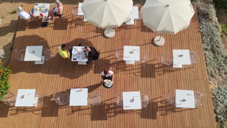 Breakfast-outdoors-with-people-enjoying-eating-and-drinking-and-waitress-serving