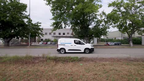 Business-minivan-seen-from-the-side-on-an-industrial-complex-road,-Aerial-dolly-right-side-view