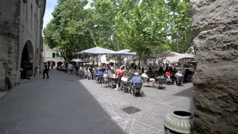 Gente-Disfrutando-De-Un-Café-Al-Aire-Libre-En-La-Plaza-Principal-De-La-Ciudad-De-Hierbas,-Toma-De-Cámara-Lenta-A-La-Izquierda