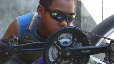 Medium-shot-of-a-young-adult-with-buck-teeth-checking-and-inspecting-his-upside-down-bike