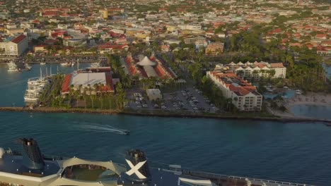 Aerial-view-of-the-city-at-coastline-with-a-close-backwards-fly-over-the-cruise-ship