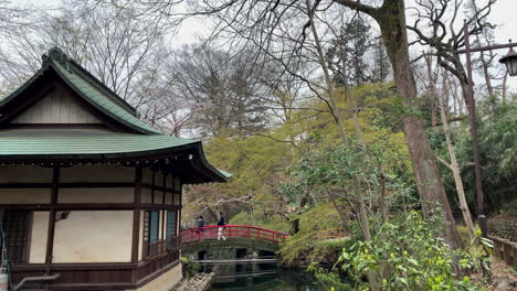 Detrás-Del-Santuario-Inokashira-Benzaiten-Frente-A-Un-Lago-Con-Un-Puente-Rojo