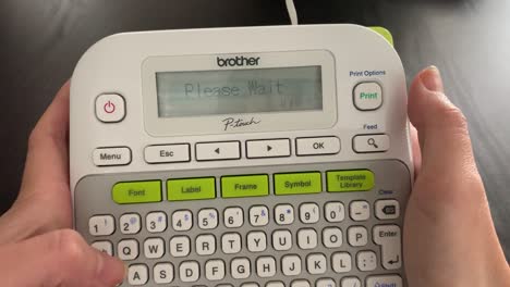 Hand-printing-out-a-simple-white-label-with-black-text-using-a-small-portable-label-maker